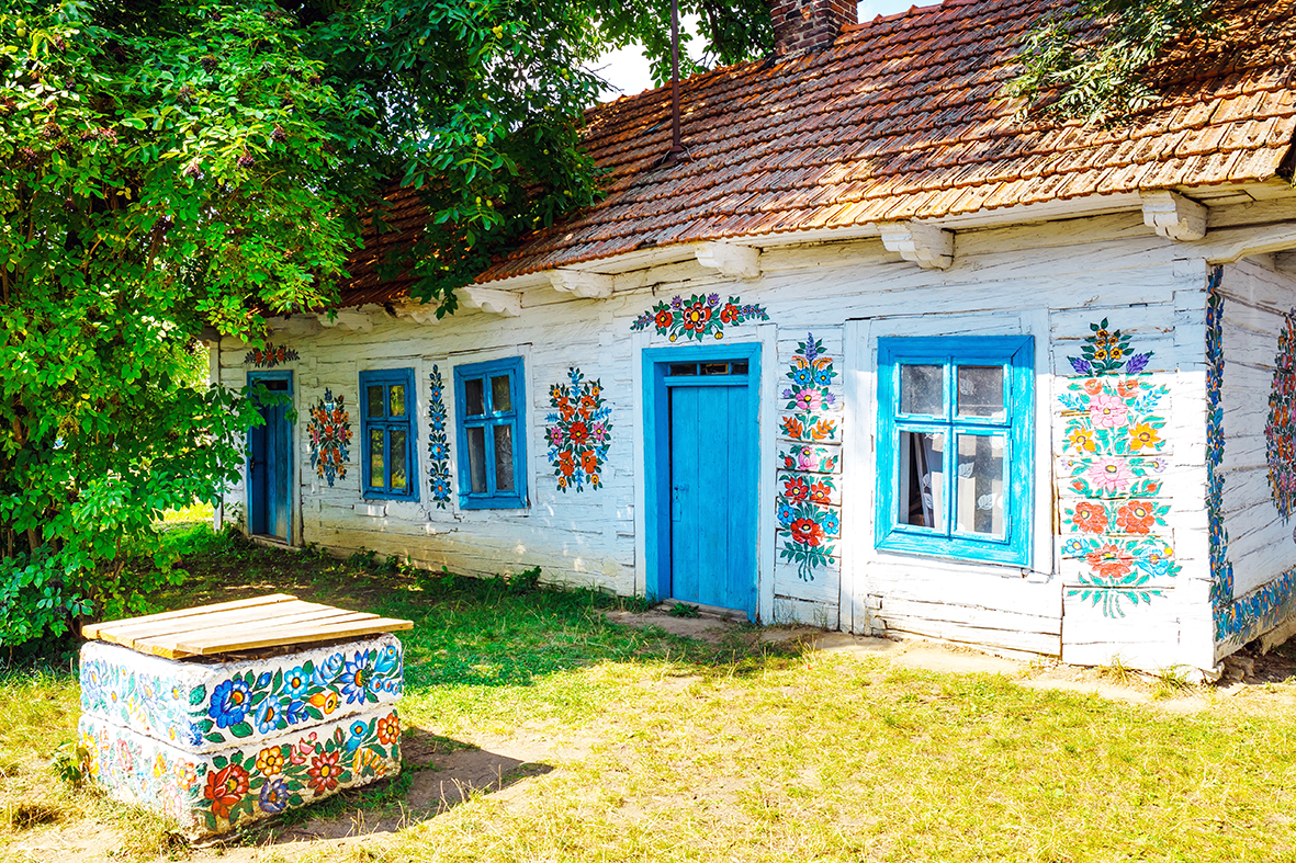 Zalipie, Poland, August 19, 2018:  Colourful house with flowers painted on walls and sundial in the village of Zalipie, Poland. It is known for a local custom of painting the cottages with decorative motifs