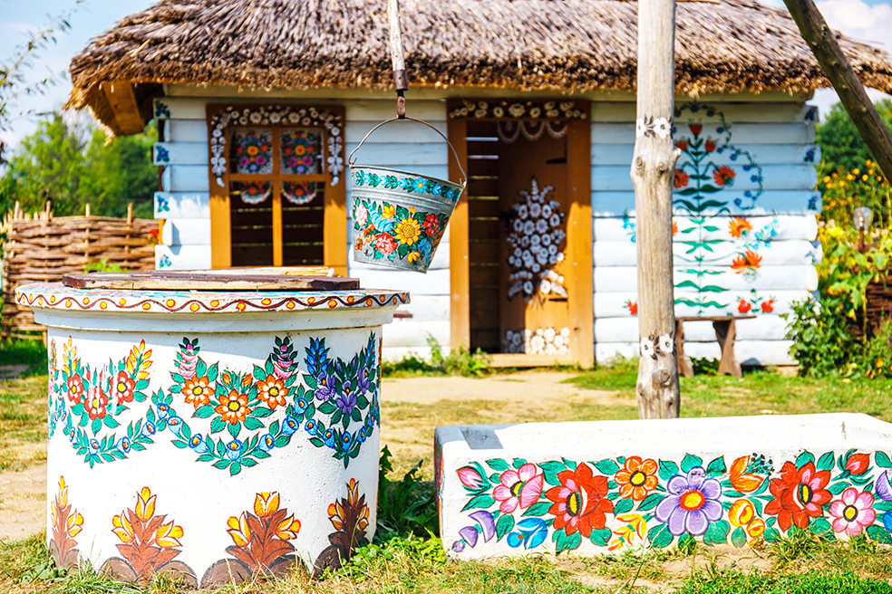 Zalipie, Poland, August 19, 2018: traditional farmstead with a well in the colorful village of Zalipie, Poland. It is known for a local custom of painting the cottages with decorative motifs